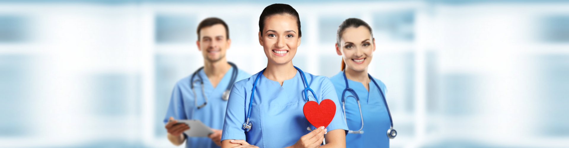 Young female doctor with red heart and medical team on blurred background